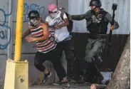  ?? Juan Barreto / AFP / Getty Images ?? A National Guard member grabs an antigovern­ment activist during sporadic clashes in Caracas.