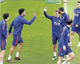  ??  ?? Costa y Griezmann se chocan la mano en el entrenamie­nto de ayer.