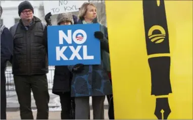  ?? JACQUELYN MARTIN — THE ASSOCIATED PRESS ?? Melinda Pierce, center, with the Sierra Club, holds a “No KXL” sign, next to a large poster of a pen Feb. 24, 2015 as she gathers with other opponents of Keystone XL oil pipeline to celebrate President Barack Obama’s veto of the legislatio­n outside the...