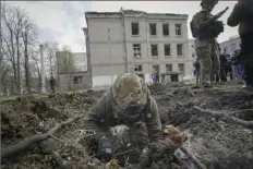  ?? Andrii Marienko/Associated Press ?? A military expert examines the site of a Russian bombing that killed several people Saturday in Kharkiv, Ukraine.