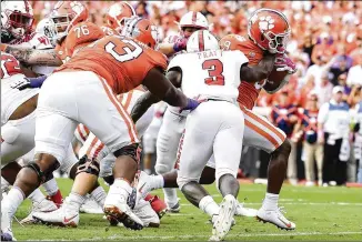  ?? MIKE COMER / GETTY IMAGES ?? Clemson running back Travis Etienne (right) runs through the tackle attempt of N.C. State linebacker Germaine Pratt to score one of his three touchdowns Saturday.