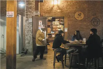  ?? Santiago Mejia / The Chronicle ?? Manager Frank Martinez walks to each table at the outdoor dining area to let customers know it’s their last call for drinks at the Old Wagon Saloon & Grill in downtown San Jose.