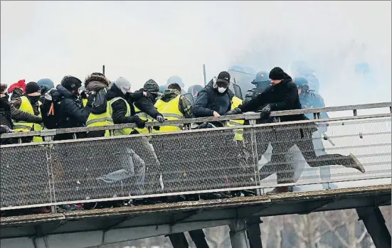  ?? IAN LANGSDON / EFE ?? Agentes antidistur­bios intentando evitar que los chalecos amarillos crucen un puente sobre el río Sena, ayer en París