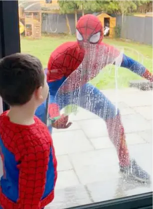  ??  ?? CLEANING UP: Spider-man, aka Chris Smalley-Ward, entertains a young fan while cleaning windows