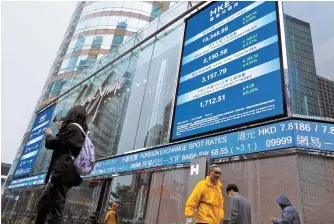  ?? Reuters-Yonhap ?? People walk past screens displaying the Hang Seng stock index and stock prices outside the Exchange Square in Hong Kong, Jan. 23.