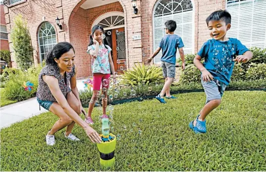  ?? DAVID J. PHILLIP/AP ?? Vicky Li Yip sets up a bubble machine for her children, from left, Kelsey, 8, Toby, 10 and Jesse, 5, outside their home in Houston. Li Yip says online schooling has been exhausting.