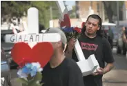  ?? Scott Olson / Getty Images ?? Neighbors in the Little Village neighborho­od of Chicago place crosses in tribute to the fire victims.