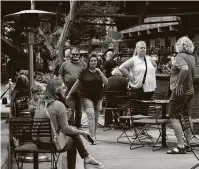  ??  ?? People, some wearing masks and some not, gather on the River Walk on Friday.