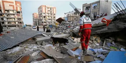  ?? AP ?? A rescue worker searches for survivors under the debris with his sniffing dog after a powerful earthquake hit the city of Sarpol-e-Zahab, Iran, near the Iran-Iraq border late on Sunday.—