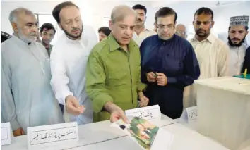  ?? — AFP ?? Shahbaz Sharif, head of Pakistan Muslim League-nawaz (PML-N), shows his ballot papers as he casts his vote during Pakistan’s general election at a polling station in Lahore on Wednesday.