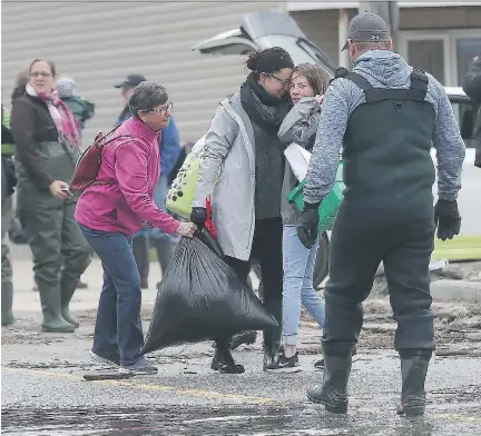  ?? PHOTOS: TONY CALDWELL ?? Two women hug before leaving rue Saint-Louis in Gatineau on Tuesday. Water levels are beginning to recede around rue Saint-Louis but homeowners in flood-affected areas are being asked to wait for the levels to recede before beginning to clean up.