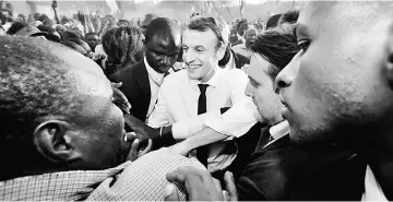  ??  ?? Macron greets people as he arrives to visit a school in Ouagadougo­u. — Reuters photo