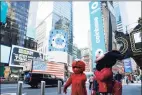  ?? Associated Press ?? Costumed characters pass the Nasdaq MarketSite during the Coinbase IPO, in New York’s Times Square on Wednesday.