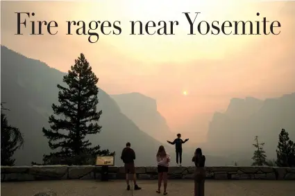  ?? Noah Berger/Associated Press ?? ■ Hannah Whyatt poses for a friend’s photo as smoke from the Ferguson fire fills Yosemite Valley on Wednesday in Yosemite National Park, Calif. Campsites and lodges emptied out after disappoint­ed tourists were ordered to leave the heart of Yosemite...