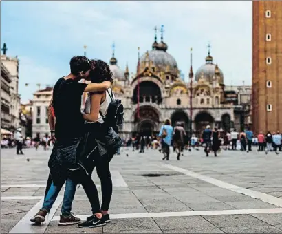  ?? LAURENT EMMANUEL / AFP ?? Una parella de turistes fent-se un petó a la plaça de Sant Marc; la foto es va fer el dia 7 d’aquest mes