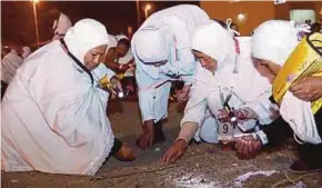  ??  ?? Malaysian pilgrims picking up pebbles for the stoning ritual in Mina yesterday.