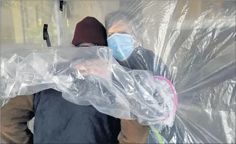  ?? THE ASSOCIATED PRESS ?? Lynda Hartman, 75, embraces her 77-year-old husband, Len Hartman, who suffers from dementia, in a “hug tent” set up outside the Juniper Village assisted living center in Louisville, Colo.