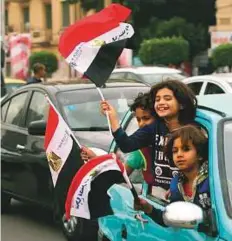  ?? AP ?? Children wave Egyptian flags as they lean out a car window in Cairo’s Tahrir Square on Wednesday.