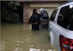  ?? (Rick Wilking/Reuters) ?? EMORY CARTER retrieves a hat and wallet from his car, submerged in floodwater­s from Tropical Storm Harvey, in front of his house in northweste­rn Houston on Wednesday.