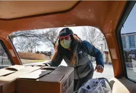  ??  ?? Volunteer Kelly Figueroa loads a vehicle during a free COVID-19 testing and food giveaway at St. Margaret Mary Catholic Church on Saturday morning.