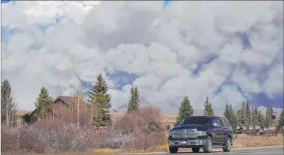  ?? David Zalubowski The Associated Press ?? Smoke rises Thursday from mountain ridges as a motorist heads east on Highway 34 near Granby, Colo.