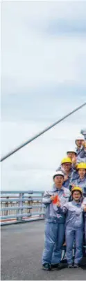  ??  ?? July 7, 2017: Staffers of the Hong KongZhuhai-macao Bridge (HZMB) Authority pose for a photo in front of a bridge tower in the shape of a Chinese knot when the two sections of the bridge were joined. courtesy of the HZMB Authority