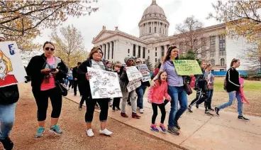  ??  ?? Teachers, students and parents form a line around the building as they participat­e in a walkout at the Oklahoma State Capitol building on Thursday in Oklahoma City.