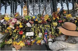  ?? Daniel Leal-Olivas / AFP / Getty Images ?? A woman places floral tributes to the victims of Wednesday’s terror attack in London. British police made a new arrest in the case on Sunday.