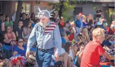  ?? ROBERTO E. ROSALES/ JOURNAL ?? Mel Alper of Corrales dons a Statue of Liberty mask and American flag shirt as he walks the parade route through the village on Tuesday.