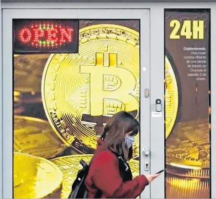  ??  ?? Criptomone­da.
Una mujer camina delante de una tienda de bitcoin en
Cracovia el pasado 2 de
enero.