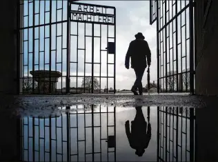  ?? MARKUS SCHREIBER/ASSOCIATED PRESS 2019 ?? A man walks through the gate of the Sachsenhau­sen Nazi concentrat­ion camp north of Berlin, Germany, with the phrase “Arbeit macht frei” (work sets you free) during Internatio­nal Holocaust Remembranc­e Day in 2019. About one-third of 80,000 Holocaust survivors in the U.S. are living in poverty, by one foundation’s estimate, and a nonprofit called KAVOD is trying to help them.