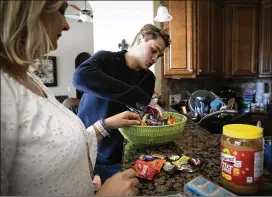  ?? CHARLOTTE KESL / FOR THE NEW YORK TIMES ?? Carolee Grodi and son Carter, 16, sort Halloween candy Friday at their home in Ocala, Florida. Carter was part of a yearlong clinical trial of an oral immunother­apy regimen that aims to reduce children’s sensitivit­y to peanut allergens by gradually exposing them to peanut protein over the course of six months.