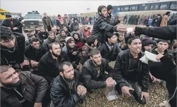  ?? Photograph­s by Marcus Yam Los Angeles Times ?? MEN GET their ID cards back after police checked them at a displaced persons camp south of Mosul.