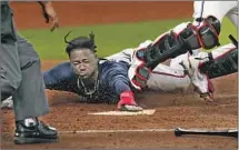  ?? Eric Gay Associated Press ?? THE BRAVES’ Ozzie Albies slides into home during the f if th inning against Miami. Atlanta has four shutouts in the playoffs.