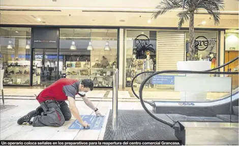  ?? CHUS MARCHADOR ?? Un operario coloca señales en los preparativ­os para la reapertura del centro comercial Grancasa.