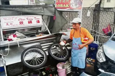  ??  ?? A hawker looking over a char koay teow pushcart stall damaged during the accident at New Lane in George Town. Eatery calamity: