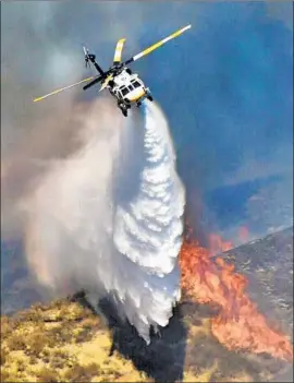  ?? Dan Watson SCV Signal ?? AN L.A. COUNTY helicopter drops retardant on the Charlie fire near Castaic. The f lames could have been even worse if the Santa Ana winds had been blowing.