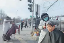  ?? WANG JING / CHINA DAILY ?? Li, a female barber, gives a senior a haircut on the roadside in Beijing’s Chaoyang district in January.