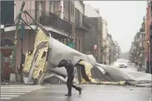  ?? Eric Gay / Associated Press ?? A man passes by a section of roof that was blown off a building in the French Quarter by Hurricane Ida’s winds on Sunday in New Orleans.
