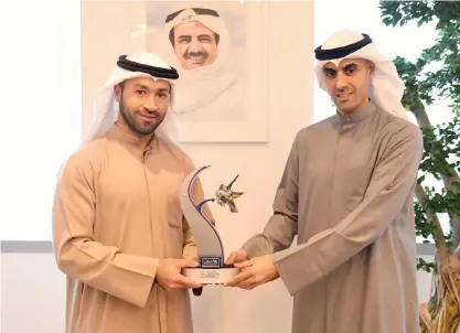  ??  ?? Zain Groupís Vice Chairman Bader Nasser Al-Kharafi honors Kuwaiti jet ski champion Yousef Al-Abdulrazza­q.