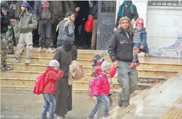  ?? — AFP ?? Syrian rebel fighters and their families arrive at a temporary shelter in the northwest province of Idlib on Friday, following their evacuation from rebel-held areas near the town of Khan al Sheikh on the outskirts of Damascus.