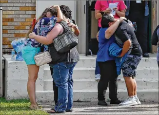  ?? MICHAEL CIAGLO / HOUSTON CHRONICLE ?? People embrace outside the Alamo Gym, where students and parents wait to reunite, following a shooting at Santa Fe High School on Friday in Santa Fe.