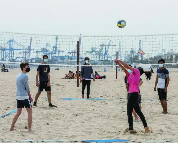  ??  ?? Jóvenes con mascarilla juegan al voleibol en la playa de la Malvarrosa de Valencia