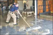  ?? NWA Democrat-Gazette/STACY RYBURN ?? Fayettevil­le firefighte­rs help to push water out of a business Thursday in Fayettevil­le. A water main near the business ruptured, shooting water into the business.