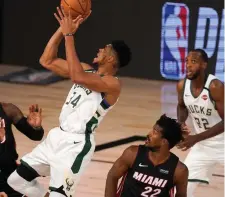  ?? AP Photo ?? MAX CONTRACT. Miami Heat’s Goran Dragic, bottom left, Jae Crowder, top left, and Jimmy Butler (22) defend as Milwaukee Bucks’ Giannis Antetokoun­mpo (34) shoots during the first half of an NBA basketball conference semifinal playoff game inin Lake Buena Vista, Fla., in this Monday, Aug. 31, 2020, file photo.