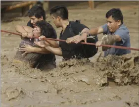  ?? AP PHOTO/MARTIN MEJIA ?? ABOVE LEFT: A group of people, stranded in flood waters, hold onto a rope as they walk to safety in Lima, Peru, on Friday. Intense rains and mudslides over the past three days have wrought havoc around the Andean nation and caught residents in Lima, a...