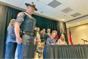  ?? AP PHOTO/JEFF AMY ?? At Lake Lanier Islands in Buford, Ga., Georgia State Trooper Trent Kirchhefer stands with K-9 officer Vilma in April as Gov. Brian Kemp signs a bill clarifying penalties for harming a police dog.