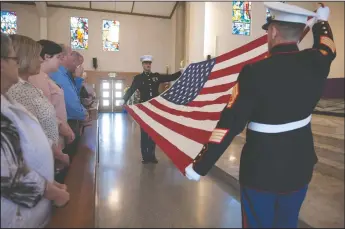  ?? NEWS-SENTINEL PHOTOGRAPH­S BY BEA AHBECK ?? Combat Logistics Battalion Capt. Jonathan Tenbrock and another CLB member unfold the American flag in front of the family of council member and former mayor Bob Johnson during a memorial service for him at St. Anne’s Catholic Church in Lodi on Thursday.
