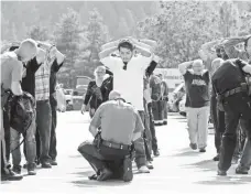  ?? MIKE SULLIVAN, NEWS-REVIEW, VIA AP ?? Police search students outside Umpqua Community College in Roseburg, Ore., on Thursday after the shootings.