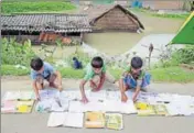  ??  ?? School students lay books out on the roads to dry them in a floodaffec­ted village in Morigaon district of Assam on Wednesday. PTI